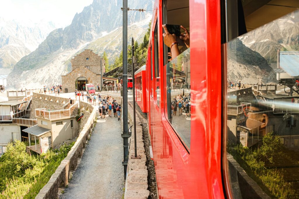 Taking photo out the window of a red train departing from Chamonix train station